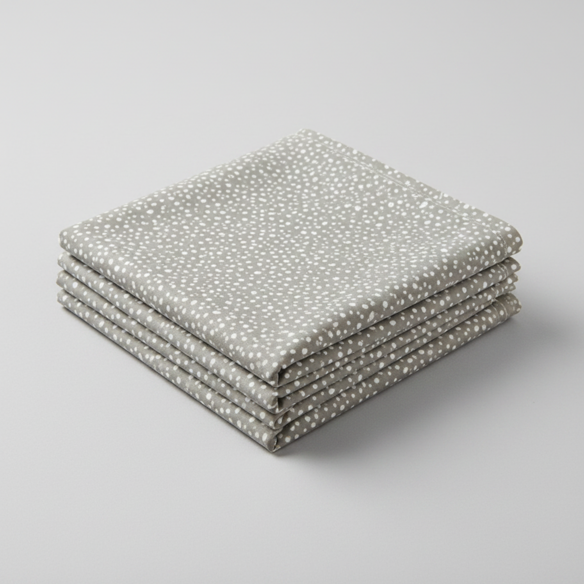 Essentials Connect The Dots Gray quilting cotton by Susan Winget for Wilmington Prints — three folded yards stacked on a grey surface, warm grey ground with tossed soft white irregular scattered dots