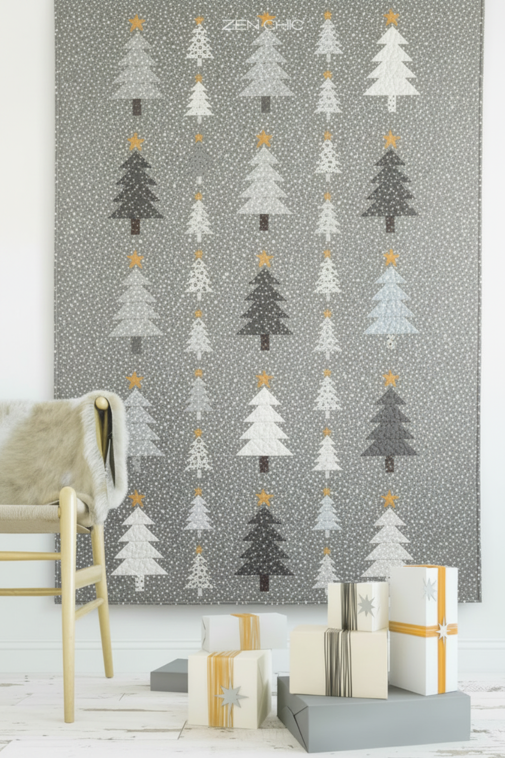 Essentials Connect The Dots Gray quilting cotton by Susan Winget for Wilmington Prints — styled in a cozy Scandinavian living room as the background of a modern Christmas tree wall hanging quilt with geometric stacked trees in grey, charcoal, and cream with gold stars, wrapped gifts below