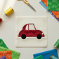 On the Go Bicycles Red quilting cotton by Jason Yenter for In The Beginning Fabrics — vertical lifestyle flat lay of a Cool Cars quilt block by Sew Kind of Wonderful made with the Quick Curve Ruler, featuring the red bicycle tone-on-tone print as the car body, with solid rainbow fabric folds, colorful thread spools, and gold scissors on a white surface. Quilts shown for inspiration. Coordinating fabrics and quilt patterns are available at IraRobi Quilts.