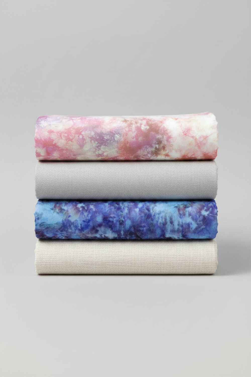 Fire & Ice by Maywood Studio cotton quilting fabric collection folded and stacked showing Peach Ice Dye and coordinating colorways on light grey background