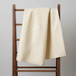 Scraps of Kindness Cream Nine Patch Boxes quilting cotton draped over a vintage wooden quilt rack — warm cream with tiny dark brown cross grid, raw cut edges, by Kim Diehl for Henry Glass