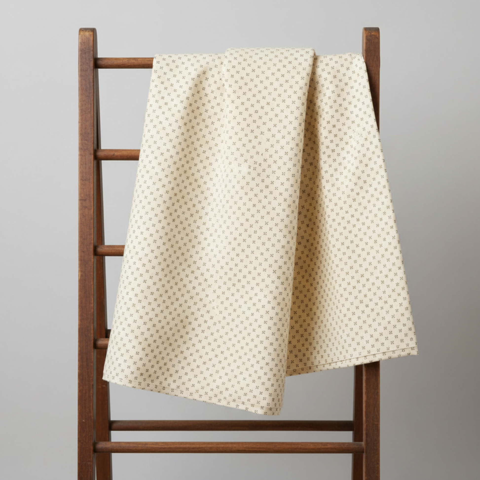 Scraps of Kindness Cream Nine Patch Boxes quilting cotton draped over a vintage wooden quilt rack — warm cream with tiny dark brown cross grid, raw cut edges, by Kim Diehl for Henry Glass