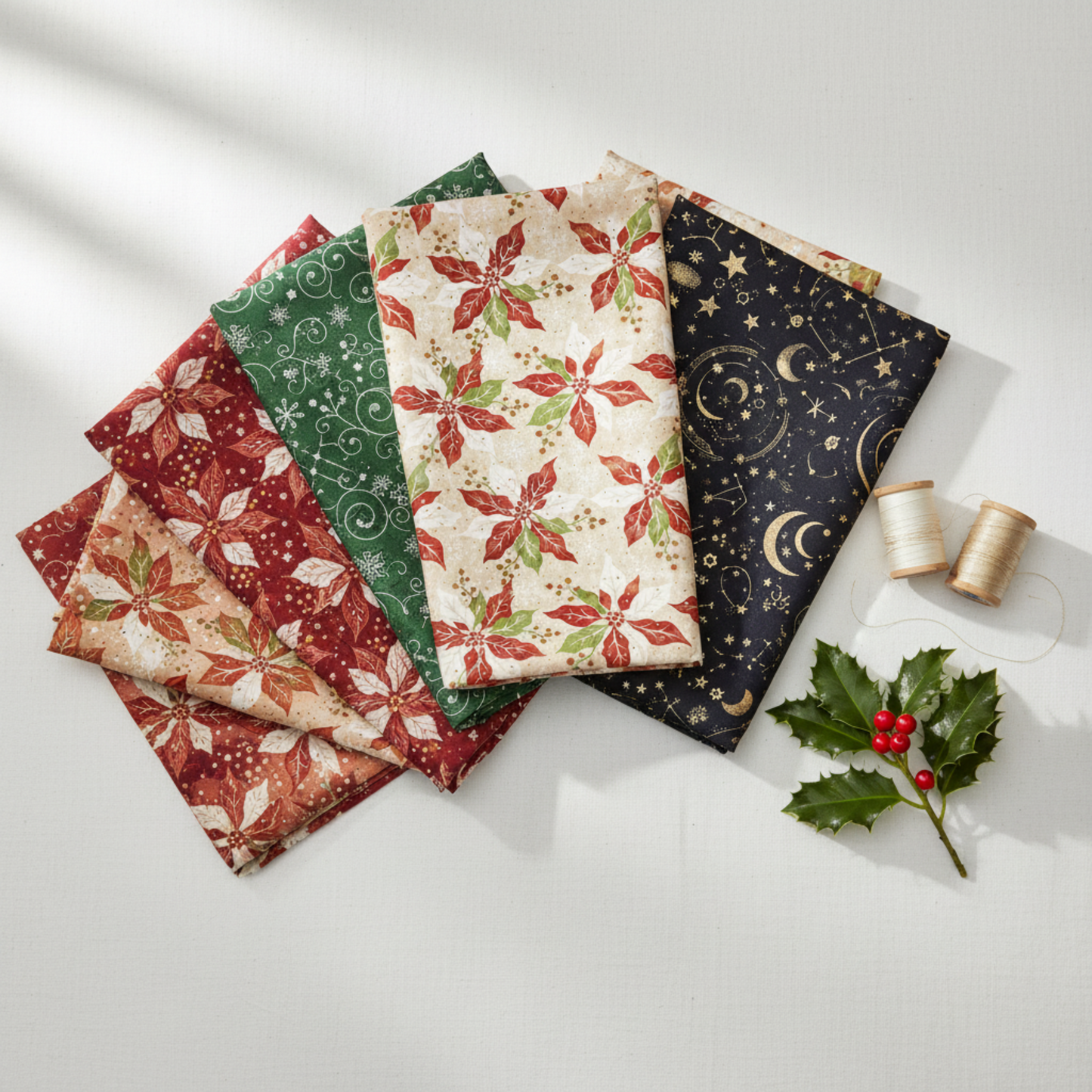 Winter Solstice II Cream Poinsettia Metallic Fabric by Jason Yenter for In The Beginning Fabrics — shown with coordinating quilting cottons fanned flat, with cream and gold metallic thread spools and a holly sprig. Coordinating fabrics and quilt patterns are available at IraRobi Quilts.