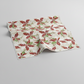 Winter Solstice II Cream Poinsettia Metallic quilting cotton by Jason Yenter for In The Beginning Fabrics — fabric draped over a grey surface showing natural folds and raw cut edge, kaleidoscopic watercolor poinsettias in red, white, and green with gold metallic berry sprigs on warm cream ground. Coordinating fabrics and quilt patterns are available at IraRobi Quilts.