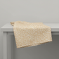 The Fox Homestead Cream Swirl Floral Texture quilting cotton by Stacy West for Henry Glass — fabric draped over a grey surface showing natural folds and raw cut edge, warm sand ground with tossed white paisley swirls and tiny rust and gold dots