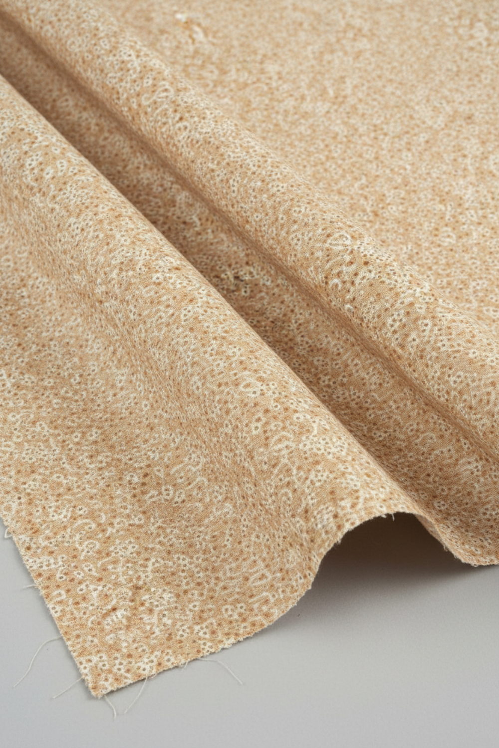 The Fox Homestead Cream Swirl Floral Texture quilting cotton in soft natural folds close-up — warm sand with white swirl print and rust dots, emphasizing fabric drape and texture, by Stacy West for Henry Glass