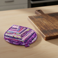 Handmade Violet Jewel leaf-shaped quilted hot pad beside a wooden cutting board | IraRobi Quilts