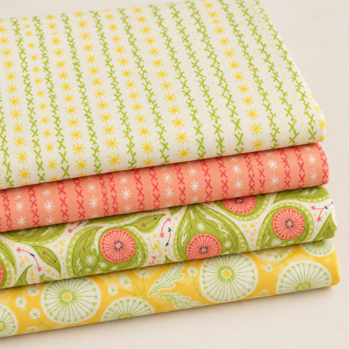 Four folded Dandi Duo fabrics in cream, peach, green paisley, and golden-yellow dandelion prints.
