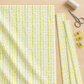Dandi Duo Cream fabric and matching cut strips on a light wood sewing table beside thread, scissors, and fabric clips.