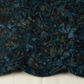 Close-up of Color Play Mottled Rainstorm fabric by Riley Blake Designs, softly draped on a light surface to show its dark blue-teal and olive mottled texture.