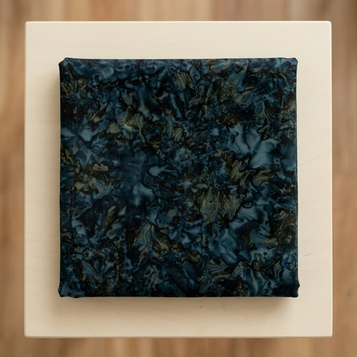 Folded Color Play Mottled Rainstorm fabric by Riley Blake Designs on an ivory surface, showing deep blue-teal, charcoal, and olive tones.