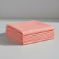 Dotty Thatched Carnation quilting cotton by Robin Pickens for Moda Fabrics — neatly folded in a stack on a light grey background showing the warm coral-pink ground with scattered tonal dots. 100% cotton, 43–44" wide. Available at IraRobi Quilts.