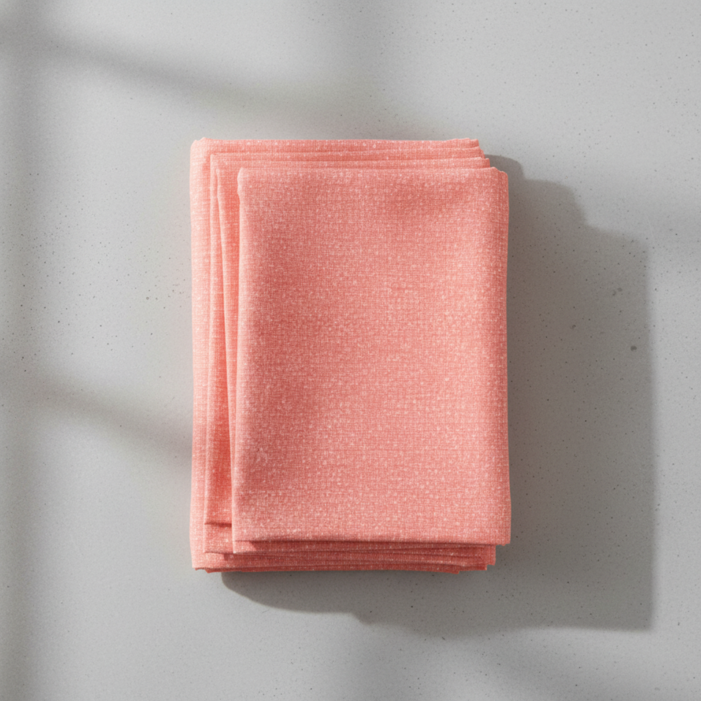 Dotty Thatched Carnation quilting cotton by Robin Pickens for Moda Fabrics — neatly folded in a stack on a light grey background showing the warm coral-pink ground with scattered tonal dots. 100% cotton, 43–44" wide. Available at IraRobi Quilts.