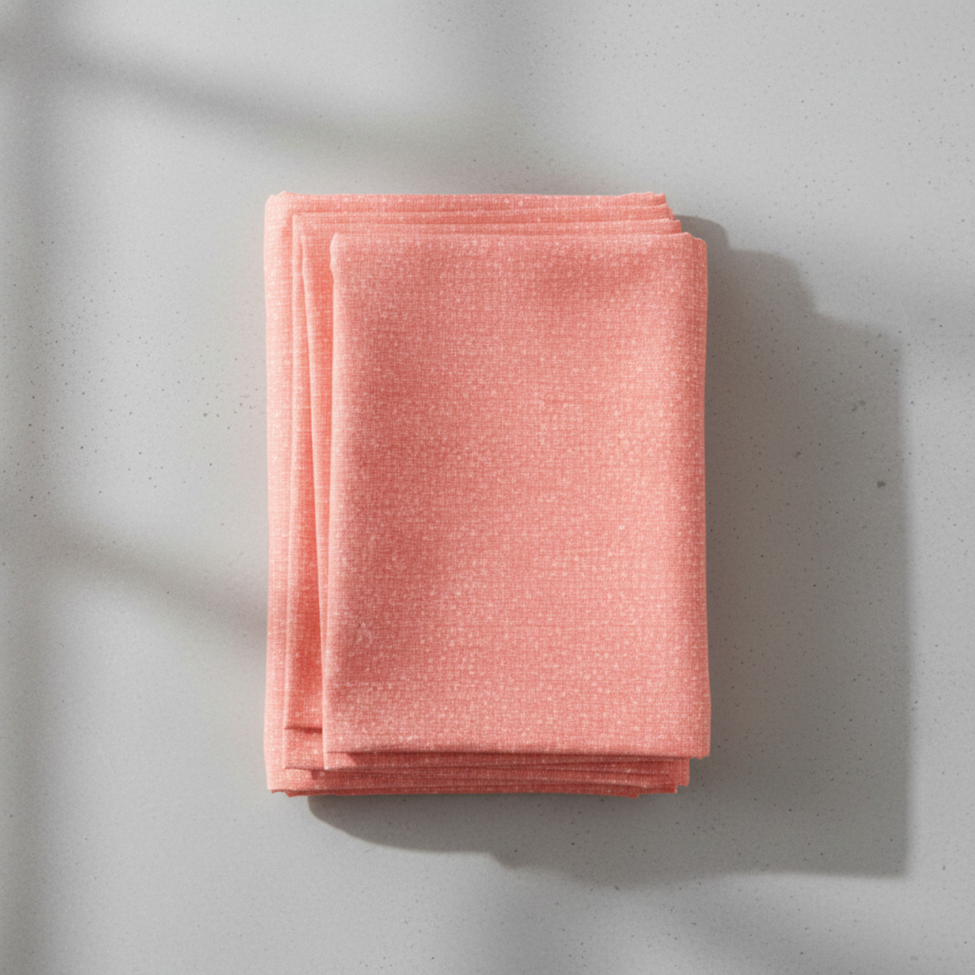 Dotty Thatched Carnation quilting cotton by Robin Pickens for Moda Fabrics — neatly folded in a stack on a light grey background showing the warm coral-pink ground with scattered tonal dots. 100% cotton, 43–44" wide. Available at IraRobi Quilts.