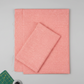 Dotty Thatched Carnation quilting cotton by Robin Pickens for Moda Fabrics — partially folded fabric on a light grey surface with a cutting mat corner and rotary cutter. Warm coral-pink ground with scattered tonal dots and crosshatch texture. Coordinating fabrics and quilt patterns available at IraRobi Quilts.