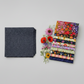Dotty Thatched Indigo fabric by Robin Pickens for Moda Fabrics — deep indigo-charcoal with scattered tonal grey dots — shown beside a coordinating stack of Wild Blossoms quilting cotton fabrics by Robin Pickens for Moda Fabrics with fresh botanical flowers. 100% cotton, 43–44" wide. Coordinating fabrics and quilt patterns available at IraRobi Quilts.