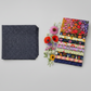 Dotty Thatched Indigo fabric by Robin Pickens for Moda Fabrics — deep indigo-charcoal with scattered tonal grey dots — shown beside a coordinating stack of Wild Blossoms quilting cotton fabrics by Robin Pickens for Moda Fabrics with fresh botanical flowers. Coordinating fabrics available at IraRobi Quilts.
