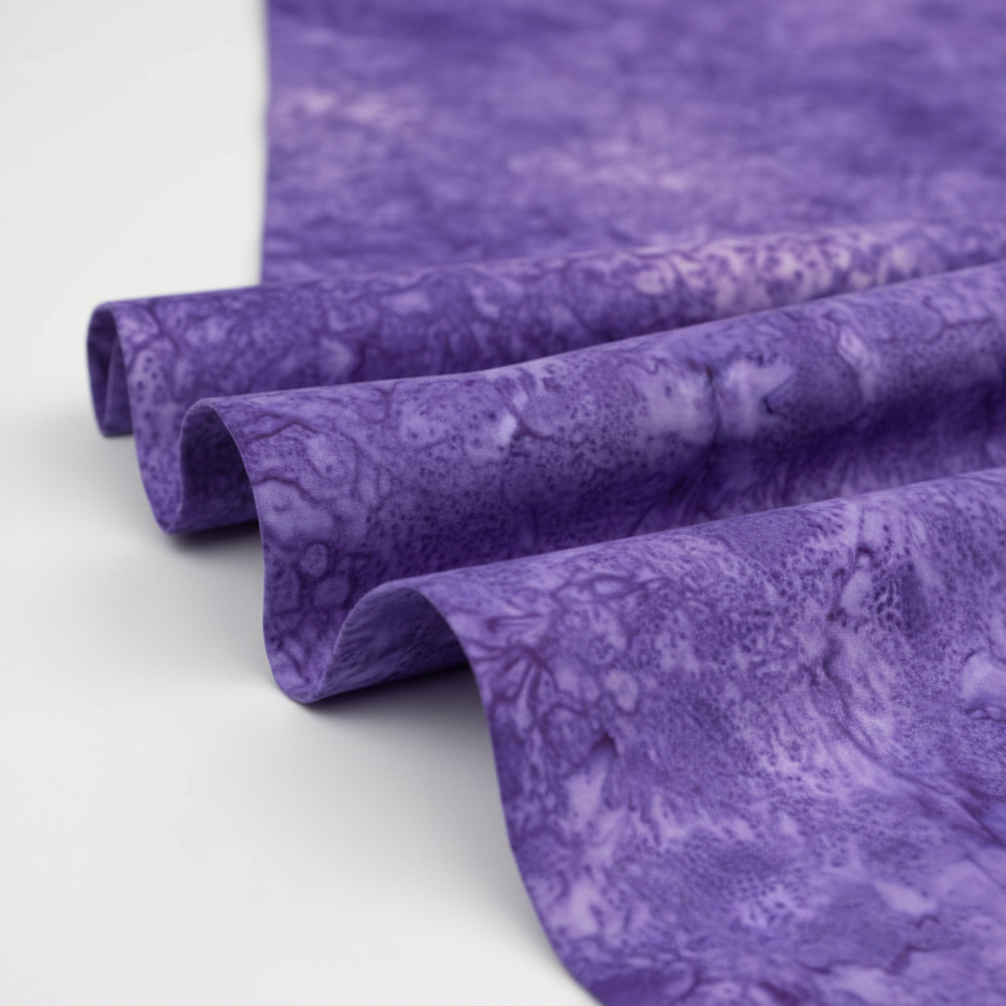 Expressions Batiks Hand-Dyes Purple II fabric draped to show organic tonal variation and hand-dyed batik texture – rich violet-purple 100% cotton quilting fabric by Riley Blake Designs