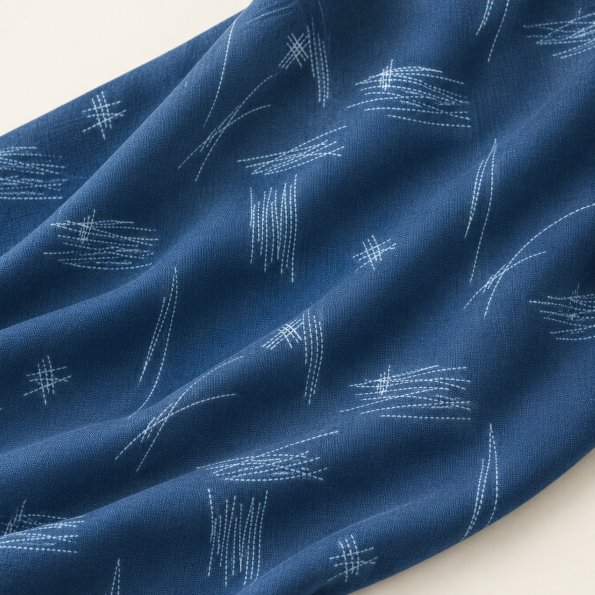 Bluish Stitched Up Blueprint quilting cotton draped in soft folds, showing pale stitched arcs and crosshatches on blue.