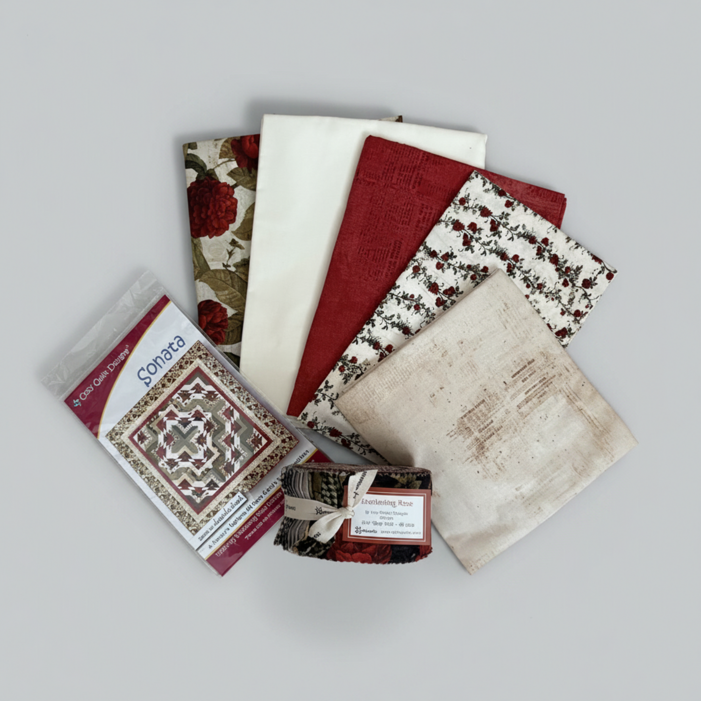 Everlasting Rose Quilt Top Kit – five folded cotton fabrics, Everlasting Rose 2.5" strip roll by Iron Orchid Designs for Clothworks, and Sonata quilt pattern by Cozy Quilt Designs on light grey background