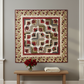 Everlasting Rose Sonata quilt hung on a neutral grey wall above a wooden console table with red roses and folded cream throw – full medallion design in crimson, cream and burgundy