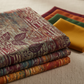 Falling Leaves Multi Leaf Stripe fabric by Jason Yenter for In The Beginning Fabrics folded on a linen surface – dramatic botanical leaf silhouettes and fern fronds over vertical stripe geometric background in jewel tones of burgundy, plum, purple, and teal, perfect for bold autumn quilt projects, 100% cotton, 3 yard cut