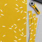 Filigree Rice Saffron fabric by Zen Chic for Moda Fabrics laid flat with cut strips, a rotary cutter, a clear quilting ruler, and a folded charcoal coordinating fabric. Available at IraRobi Quilts.