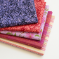 Stack of five coordinating Superbloom fabrics by Robin Pickens for Moda Fabrics: Leafy Indigo, Leafy Geranium, Daisyish Freesia, and Scribble Stripe in Orchid and Cream.