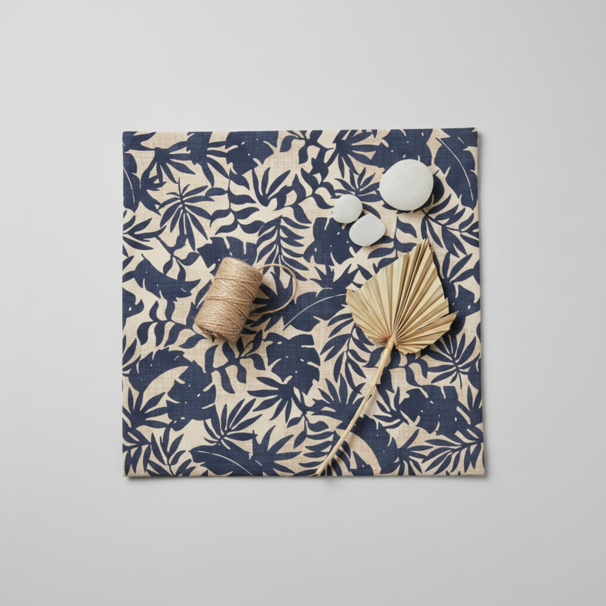 Breezeway Textured Palms Blue/Cream quilting cotton by Maywood Studio — coastal flat lay with sea glass, cotton twine, and dried palm sprig on cream ground with bold navy-blue palm and monstera silhouettes