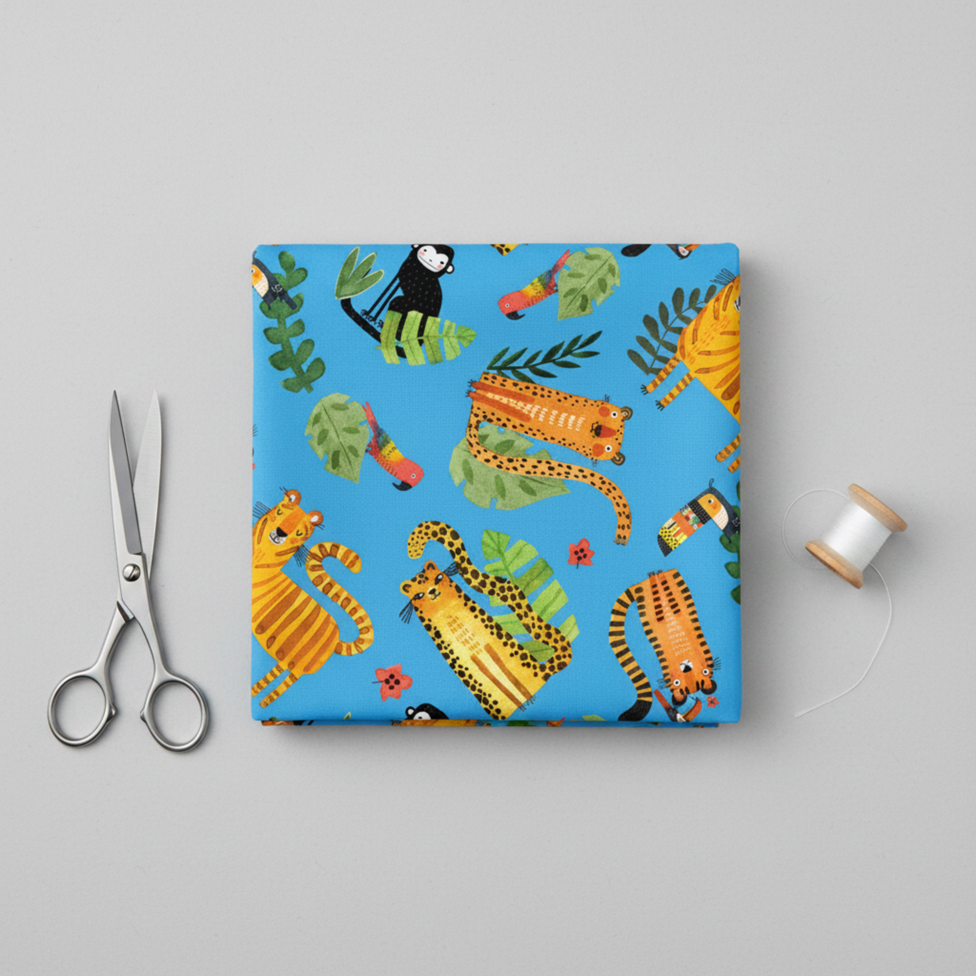 Safari Fun Playful Safari Blue quilting cotton folded flat with fabric scissors and thread spool on light grey background — whimsical tigers, leopards, monkeys, toucans, and parrots by Terry Runyan for Benartex