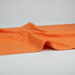 Safari Fun Floating Triangles Orange by Terry Runyan for Benartex – fabric softly draped showing hand and weight of the quilting cotton, light grey background