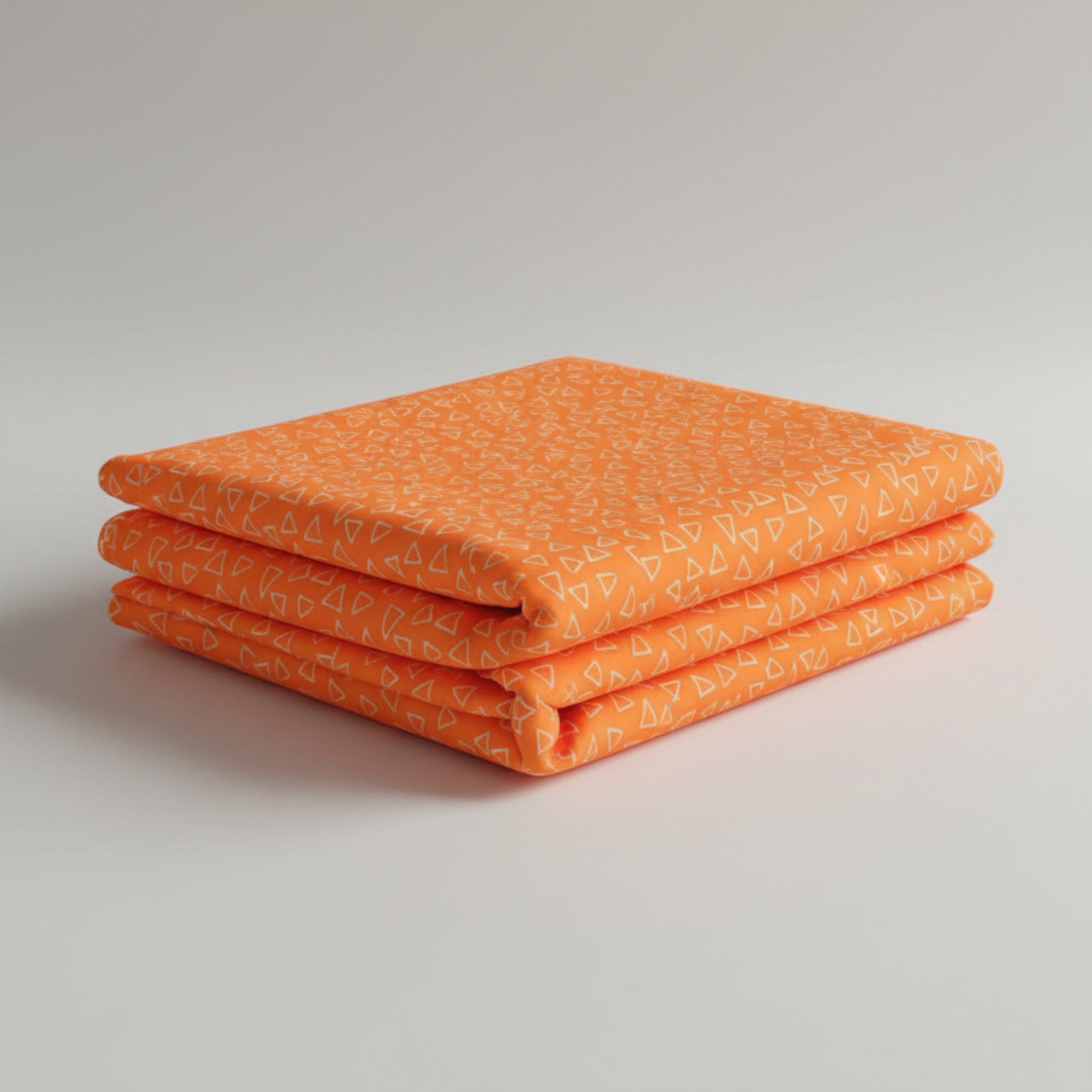 Safari Fun Floating Triangles Orange by Terry Runyan for Benartex – neatly folded fabric stack photographed at an angle, showing triangle print and fabric weight, light grey background