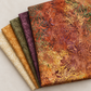 Folded Windsong Floral Medallions Sienna fabric with coordinating cream, ochre, olive, and plum batik swatches.