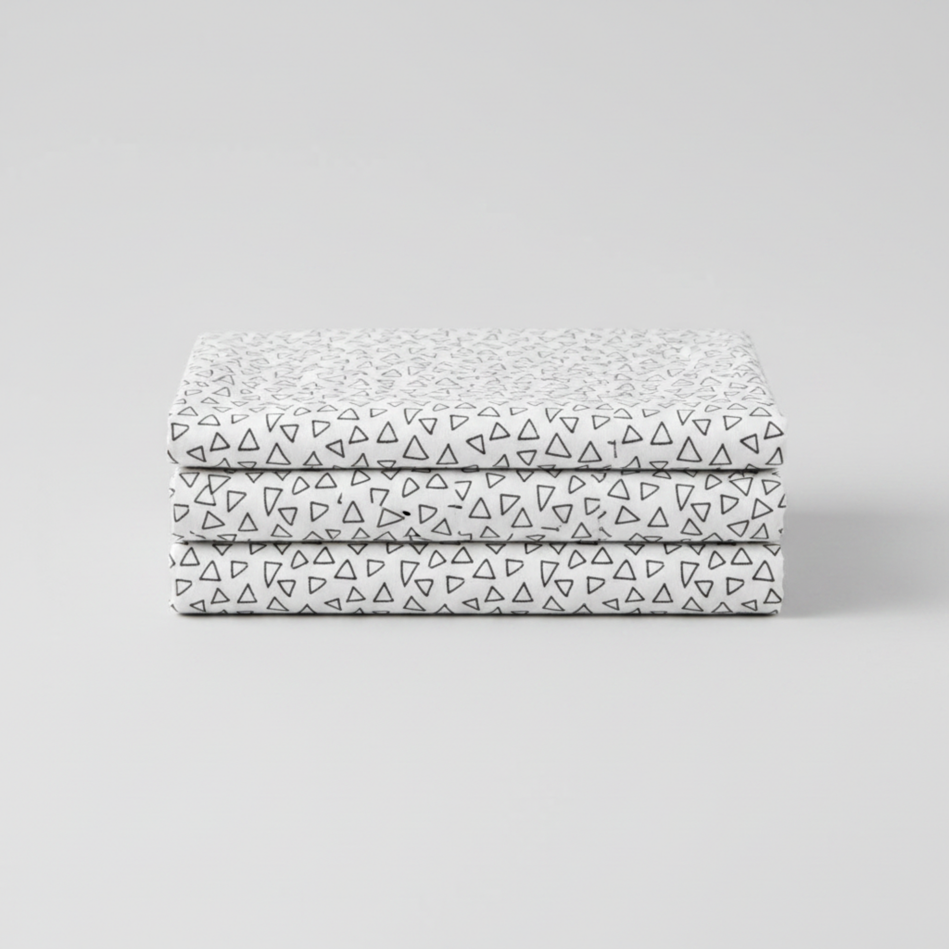 Safari Fun Floating Triangles White/Black fabric folded and stacked — black hand-drawn triangle outlines on white quilting cotton by Terry Runyan for Benartex. 100% cotton, 43–44" wide