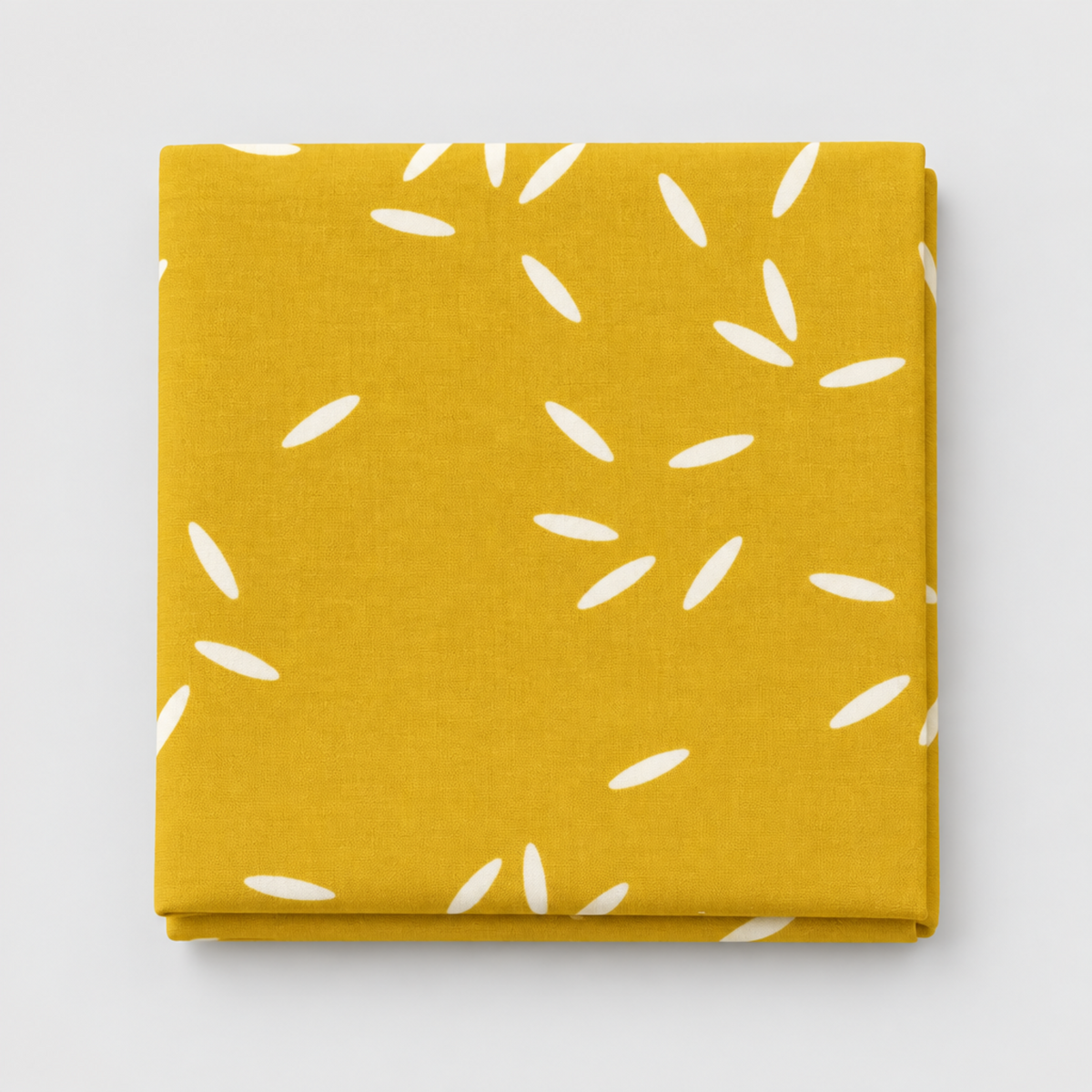 Filigree Rice Saffron fabric by Zen Chic for Moda Fabrics, neatly folded on a light grey background, showing white rice-grain shapes scattered across a saffron-mustard ground.