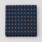 Frisky In A Row Moody fabric by Zen Chic for Moda Fabrics, neatly folded on a light grey background, showing neat rows of rust-orange dots on a deep navy ground.