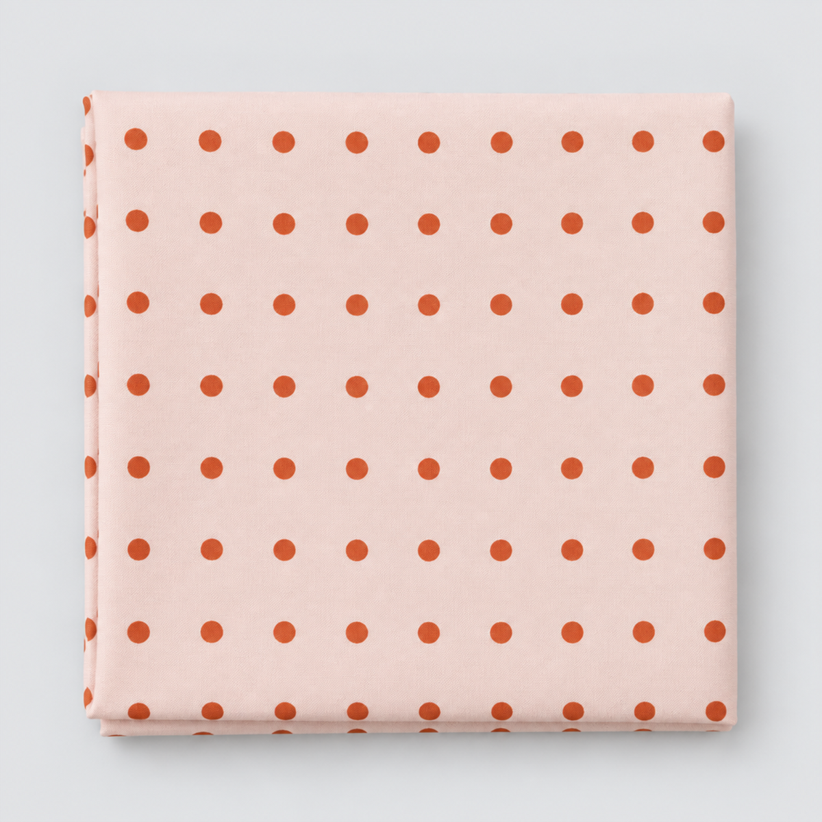 Frisky In A Row Sweetie fabric by Zen Chic for Moda Fabrics, neatly folded on a light grey background, showing neat rows of rust-orange dots on a soft blush-pink ground.