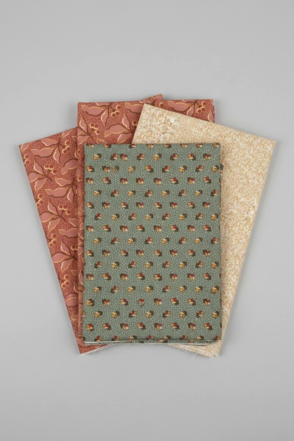 The Fox Homestead Slate Blue Green Tossed Cubes Fabric by Stacy West for Henry Glass — vertical coordination stack with Fox Homestead Pink Leaves and Berries and Cream Swirl Floral Texture fabrics fanned on a light grey background. Coordinating fabrics and quilt patterns are available at IraRobi Quilts.