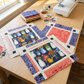 Fringe-inspired quilt blocks featuring Superbloom Flea Market Vases Indigo and coordinating leafy and striped fabrics on a sunlit sewing table, with a folded fabric stack, remnants, thread, and sewing machine. Quilt blocks shown for inspiration. Coordinating fabrics and quilt patterns are available at IraRobi Quilts.