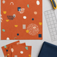 Frisky Catch Me Cheeky fabric by Zen Chic for Moda Fabrics laid flat with cut squares, a rotary cutter, a clear quilting ruler, and a folded navy coordinating fabric. Available at IraRobi Quilts.