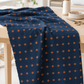 Frisky In A Row Moody fabric by Zen Chic for Moda Fabrics draped over a wooden sewing table in a bright studio with thread, a pin dish, and scissors. Available at IraRobi Quilts.