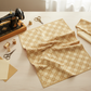 Golden Era Floral Plaid Tan quilting cotton by Paula Barnes for Marcus Fabrics — styled sewing room flat lay with tan-gold lattice fabric alongside vintage sewing machine, gold and cream thread spools, scissors, thimble, and coordinating cream and tan fabric swatches