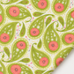 Dandi Duo Grass fabric laid flat with one folded corner, showing its green paisley and coral-pink floral print.