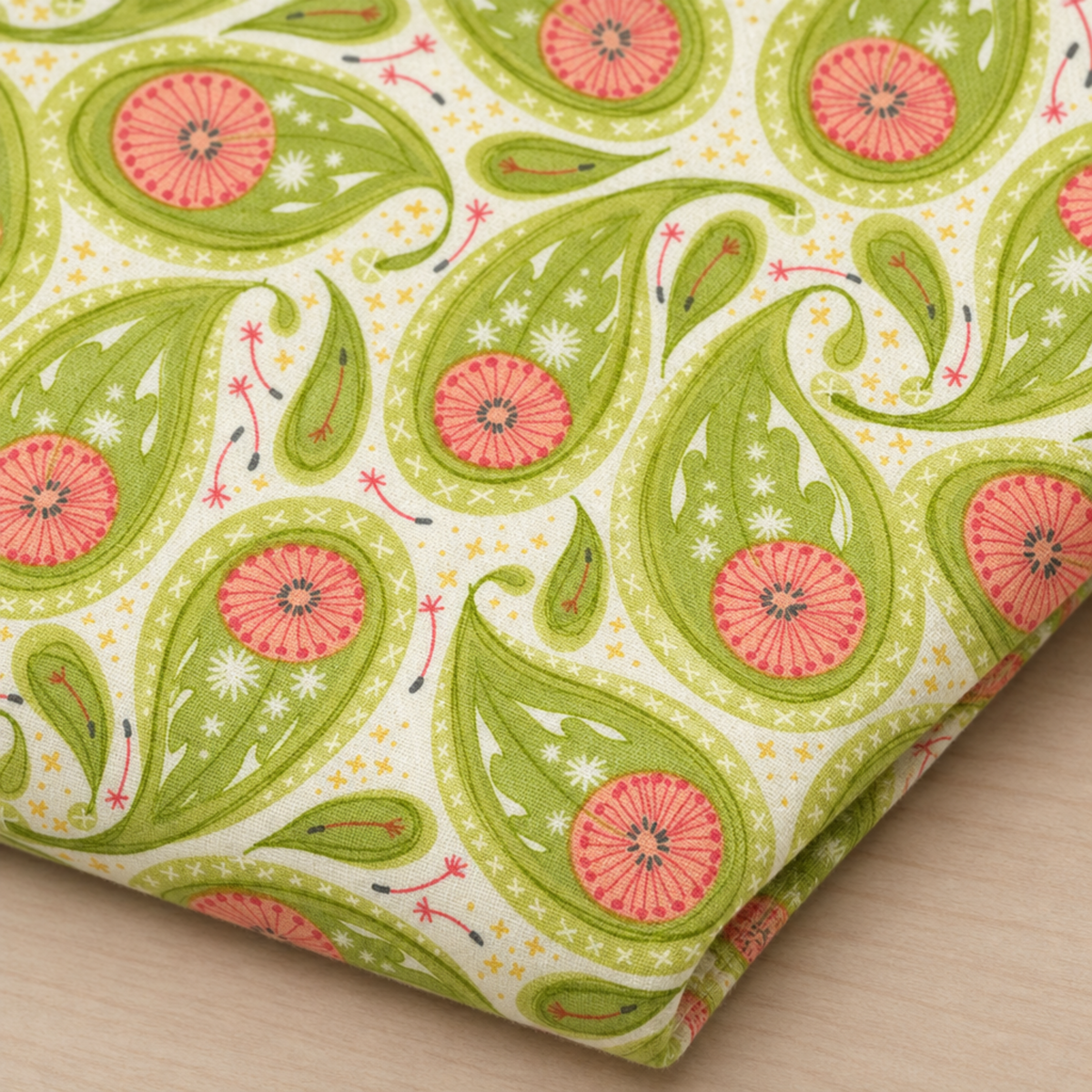 Folded Dandi Duo Grass fabric showing green floral paisleys and coral-pink flowers on a cream ground.