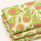 Close view of folded Dandi Duo Grass fabric, showing its green paisley leaves and pink floral details on cream.