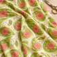 Folds of Dandi Duo Grass fabric showing green floral paisleys and coral-pink flowers on a cream ground.
