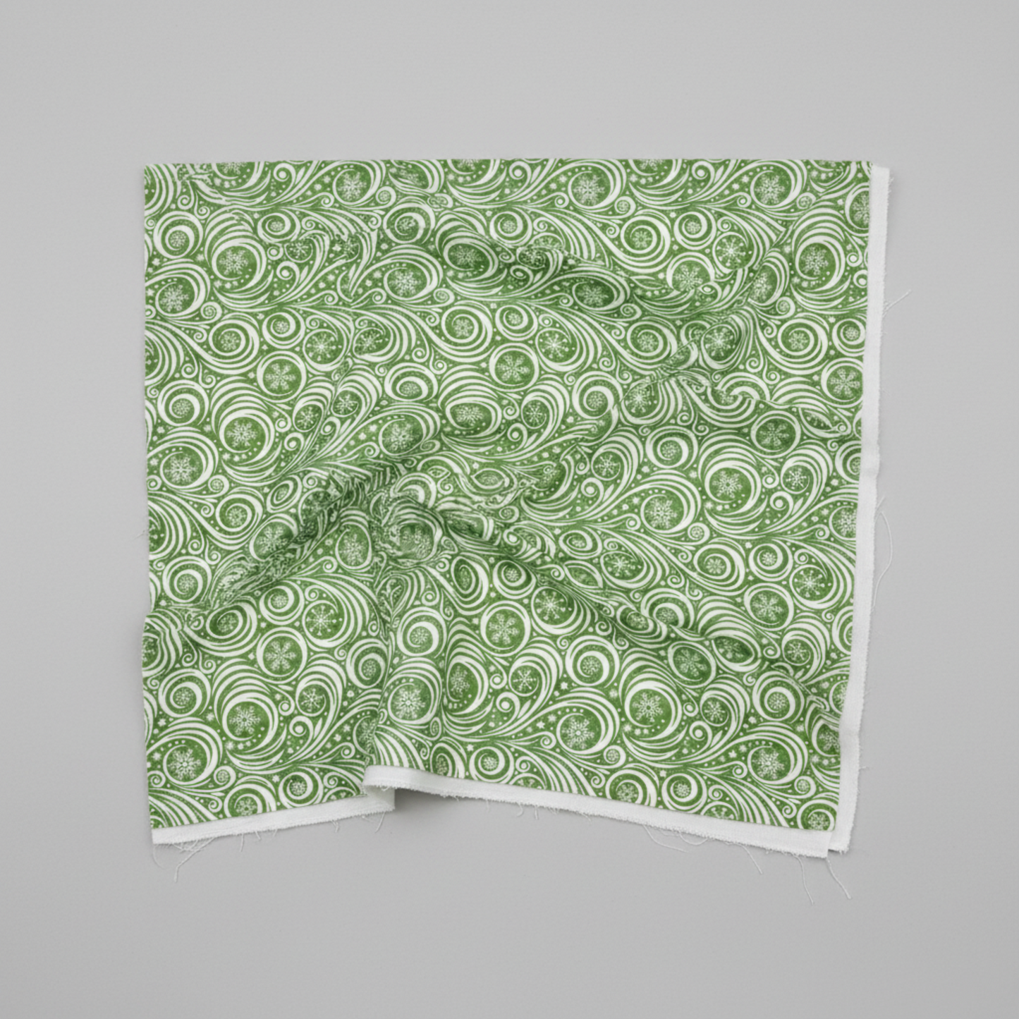 Winter Solstice II Green on White Snow Swirl quilting cotton by Jason Yenter for In The Beginning Fabrics — fabric draped over a grey surface showing natural folds and raw cut edge, flowing white scroll swirls with snowflakes and stars on mottled watercolor green. Quilt blocks shown for inspiration. Coordinating fabrics and quilt patterns are available at IraRobi Quilts.
