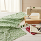 Winter Solstice II Green on White Snow Swirl quilting cotton by Jason Yenter for In The Beginning Fabrics — fabric draped alongside a vintage sewing machine with green and white thread spools, scissors, and coordinating crimson and cream fabric swatches in a cozy holiday sewing room. Coordinating fabrics and quilt patterns are available at IraRobi Quilts.