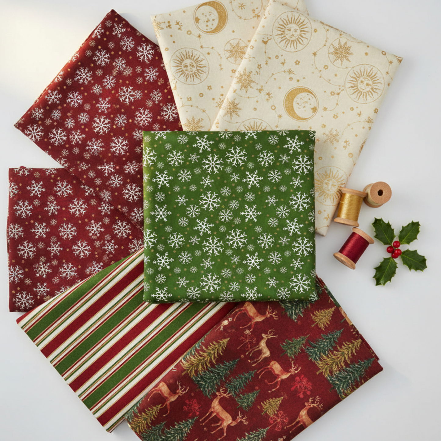 Five fabrics fanned flat featuring green snowflakes metallic, crimson snowflakes metallic, cream celestial metallic, multi stripe metallic, and multi deer metallic, with gold and red thread spools and holly sprig. Quilt blocks shown for inspiration. Coordinating fabrics and quilt patterns are available at IraRobi Quilts.