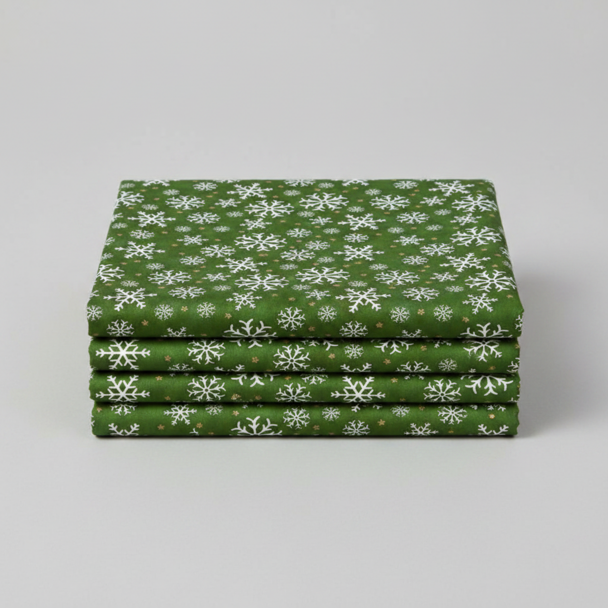 Winter Solstice II Green Snowflakes Metallic quilting cotton by Jason Yenter for In The Beginning Fabrics — three folded yards stacked on a grey surface showing rich deep forest green ground with tossed white snowflakes and gold metallic star dots. Quilt blocks shown for inspiration. Coordinating fabrics and quilt patterns are available at IraRobi Quilts.